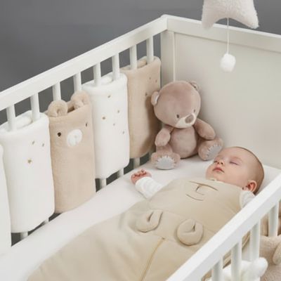bébé endormi paisiblement dans son lit avec tour de lit peluche beige crème DreamCuddle™
